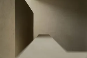 A minimalist architectural space with concrete walls and a white floor.