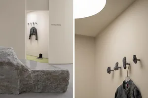 A minimalist concrete furniture platform in a fitting room with a jacket hanging on it.
