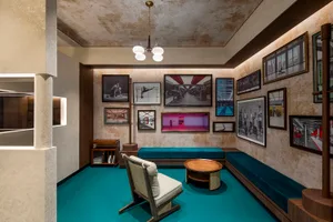 An image depicting a minimalist hotel lobby with concrete walls, wooden furniture, and turquoise accents.