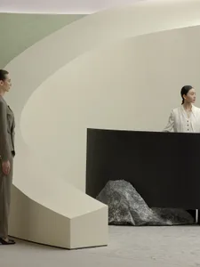 A minimalist interior design featuring a concrete structure and a woman in a white dress.