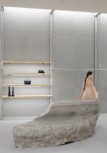 A minimalist installation featuring a large concrete sculpture in a contemporary art gallery setting.