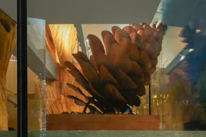 A modern metal sculpture displayed on a wooden platform, featuring intricate designs and an industrial aesthetic.