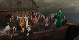 Model wearing a green coat standing on a boat surrounded by animals and people in rain.