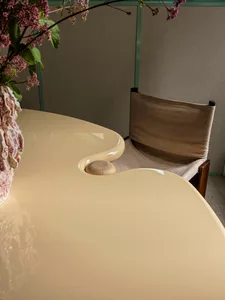 Modern dining room with ceramic table, floral arrangement, and wooden chair.