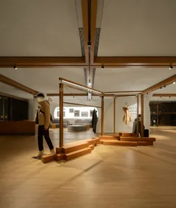 Modern retail space showcasing fashion merchandise displayed on wooden frames and wooden steps.