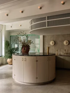 Modern kitchen with marble countertops and cabinets, featuring a central island and industrial lighting.