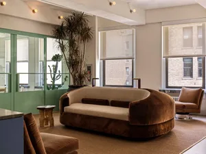 A modern living room featuring a comfortable fabric sofa with rounded edges, complemented by a sleek glass coffee table, and 
