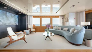 Modern residential living room featuring sofas, armchairs, and a coffee table with a vase of flowers.