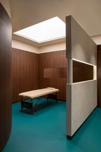 Spa treatment room featuring a wooden massage table and concrete walls