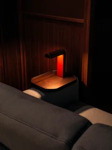A modern interior living room featuring a wooden tray table with a red lamp on it.