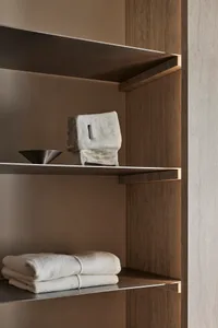Metal shelves with wooden end supports holding white towels and a decorative stone object in a bathroom storage setting.