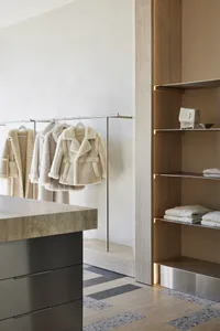 A minimalist closet with metal rod, wooden shelves, and concrete floor.