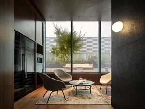 A minimalist living room featuring wooden furniture, a concrete floor, and a glass wall.