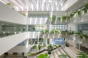 A modern office building with metal and glass features, vertical gardens, and open spaces.