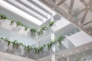 A modern office interior featuring green plants on a metallic composite wall structure.
