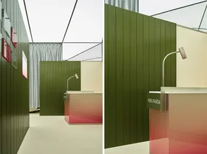 A minimalist office with green wooden walls and glass countertops.