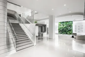 A sleek, minimalist office lobby with modern, white concrete staircase and glass railings.