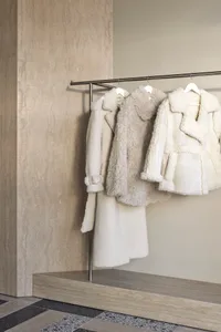 A modern coat rack features a white fabric covering, with clothes hanging on it.
