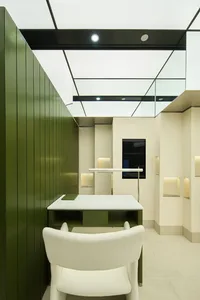 A modern office space featuring a white chair and green walls.