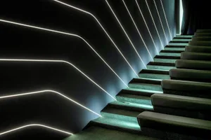 A modern luxury interior featuring a staircase with backlit metallic lighting