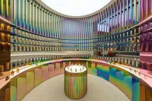 A modern retail shop featuring metallic glitter interiors with a circular perfume display and multicolored lighting.