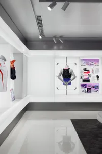 Modern retail space featuring white concrete floors, glass display cases, and minimalist design elements.