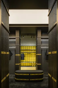 A modern retail store interior featuring concrete-tiled walls and a black seating area.