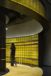 A modern retail storefront with a striking yellow-tiled wall and a curved, industrial-style ceiling.
