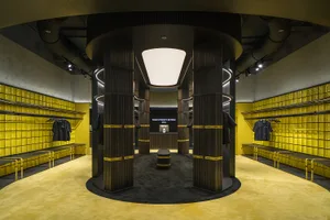 現代工業風服裝展示間，混凝土牆面、黃色瓷磚搭配黑色陳列架。