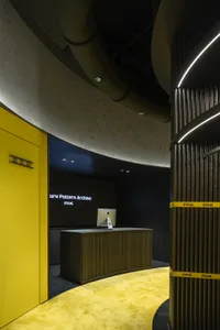 A modern, industrial-style lobby with a yellow carpet and a reception desk made of concrete.