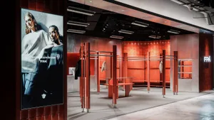 A modern retail shop featuring metallic furniture and fixtures, with a prominent advertisement for the Future Pattern Archive