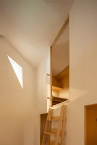 A minimalist storage space with a wooden structure and a window allowing natural light to enter.