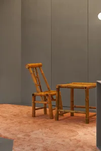A modern bamboo chair and table set on an orange carpet in a minimalist interior design space.