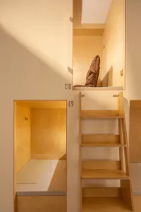 Modern industrial living space with wooden bunk beds and storage.