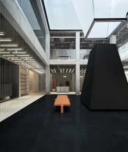 An interior office lobby with minimalist design, featuring concrete, glass, and metal materials.