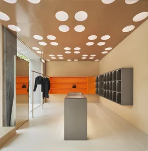 Modern retail store with concrete walls, glass shelves, and orange accents