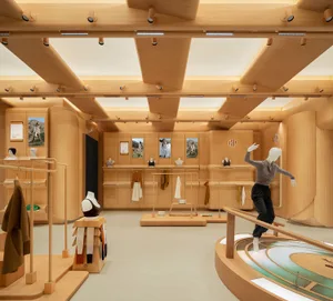 A modern retail store interior with wooden walls and shelves, a circular wooden counter, and clothing displayed on racks and