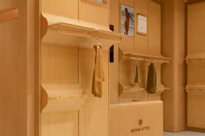 A modern retail store with wooden display shelves and clothing items hanging on them.