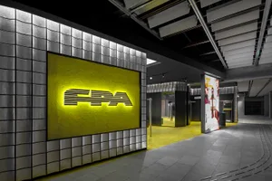 Modern retail storefront with a concrete wall and an illuminated signboard.