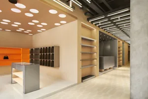 Modern retail storefront with metal shelves and orange accents on the ceiling