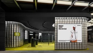 Retail storefront with metallic tile walls, black fittings, and bright yellow flooring.