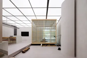 Modern minimalist living space with glass partition and white flooring.
