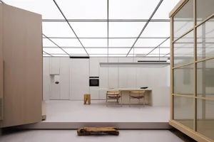 Modern kitchen with minimalist design featuring concrete countertops, glass cabinets, and wooden furniture.
