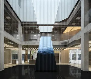 A modern lobby featuring glass walls, concrete flooring, and stone accents.