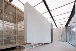A modern minimalist lobby interior featuring concrete walls, glass walls, and skylights.