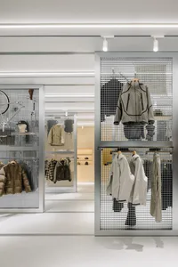 零售店面設有金屬格柵展示牆，陳列多款外套與服裝單品。
