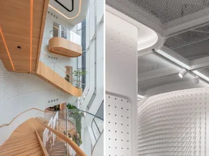 Modern building interior with a wooden staircase and perforated panels.