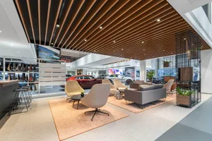 Modern interior of a car showroom featuring a wooden ceiling and comfortable seating.