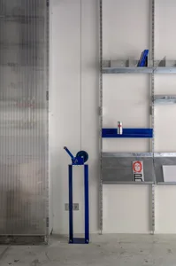 A metal bookshelf with a concrete base, holding various objects and books.