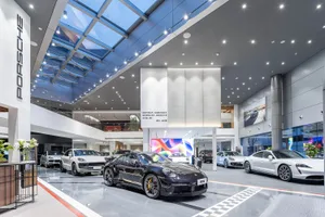 Modern car dealership showroom with sleek, polished concrete floors and large glass panels.